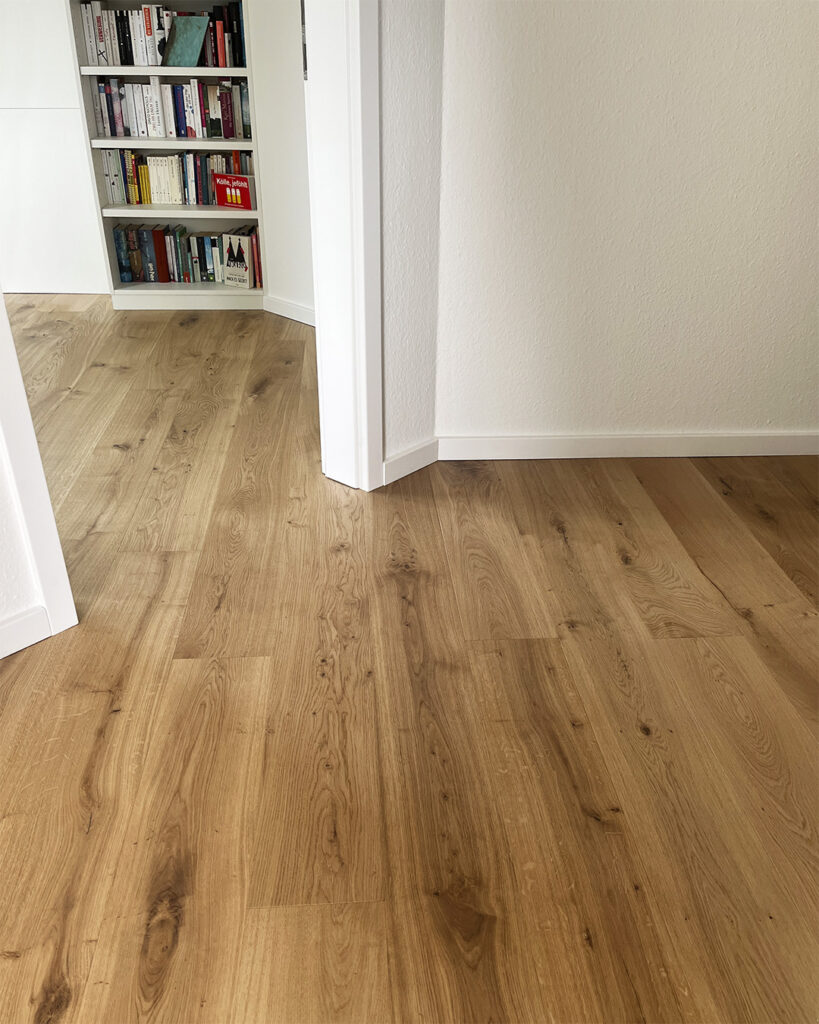 Blick in einen Flur und in ein Arbeitszimmer mit Landhausdiele in Eiche und weißen Fußleisten